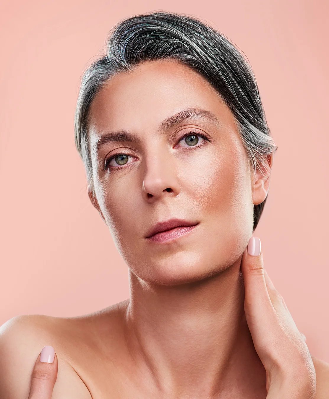 Woman with grey hair and a peach background.