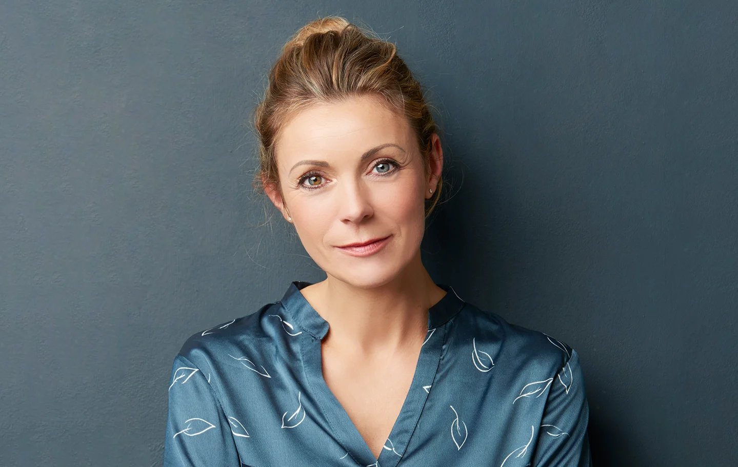 Woman posing in front of blue background.
