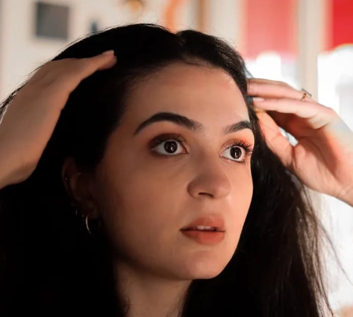Woman checking the density along her hair part